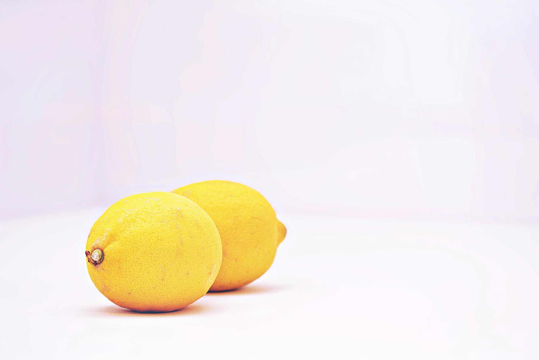 Close-up of a hand holding an orange vibrator against a minimalistic purple backdrop, showcasing modern sensuality