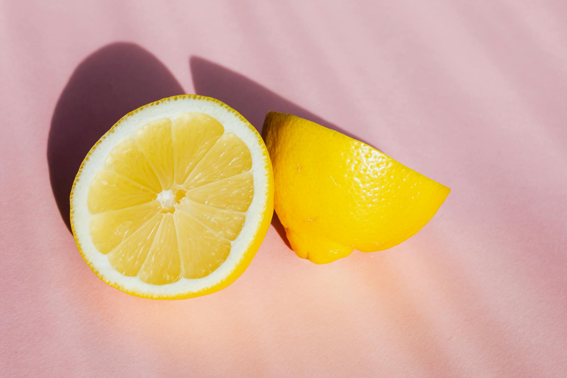 Fresh lemon halves in bright sunlight on a pink background, symbolizing the refreshed intimacy post-menopause
