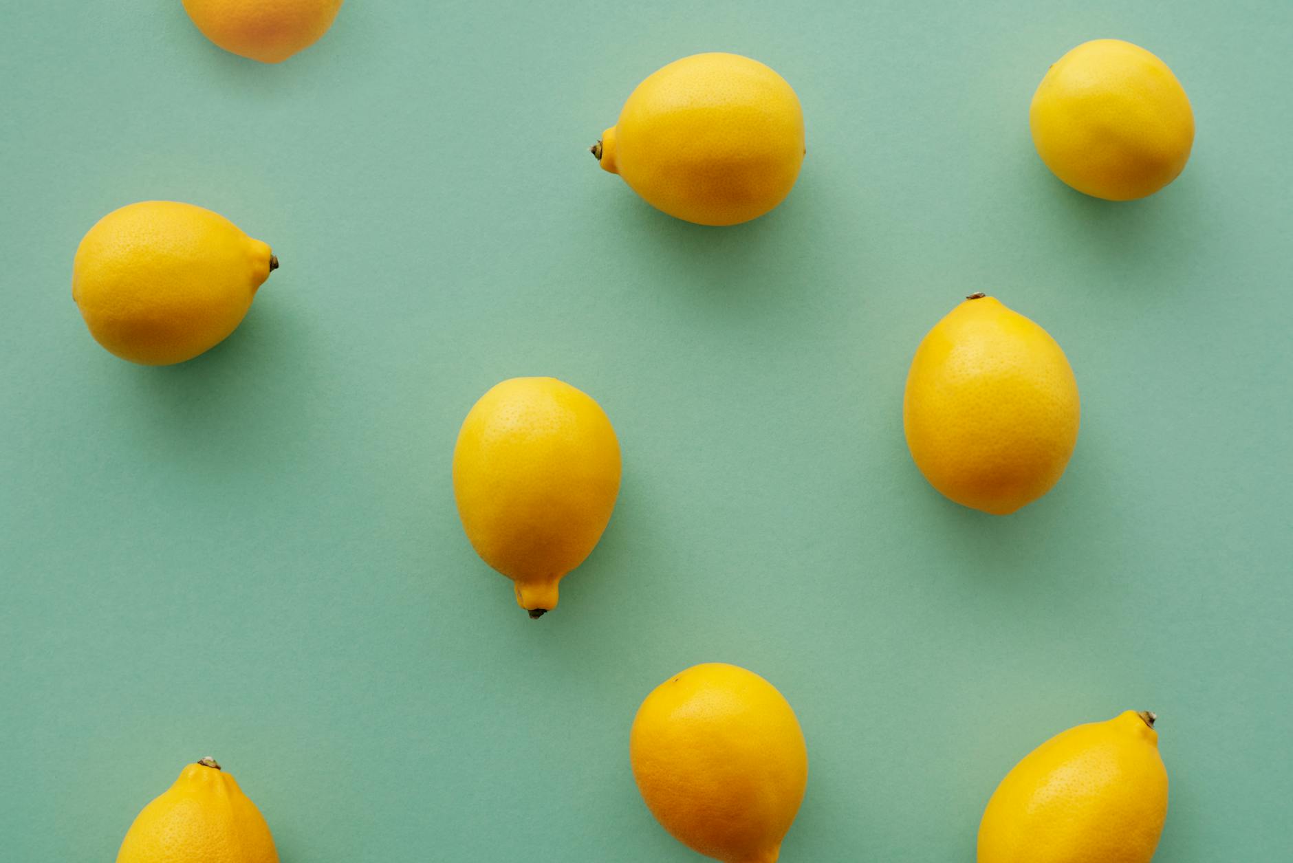 A hand holding a lemon-coloured vibrator against a minimalist purple backdrop, representing sensual pleasure and modern sexual wellness