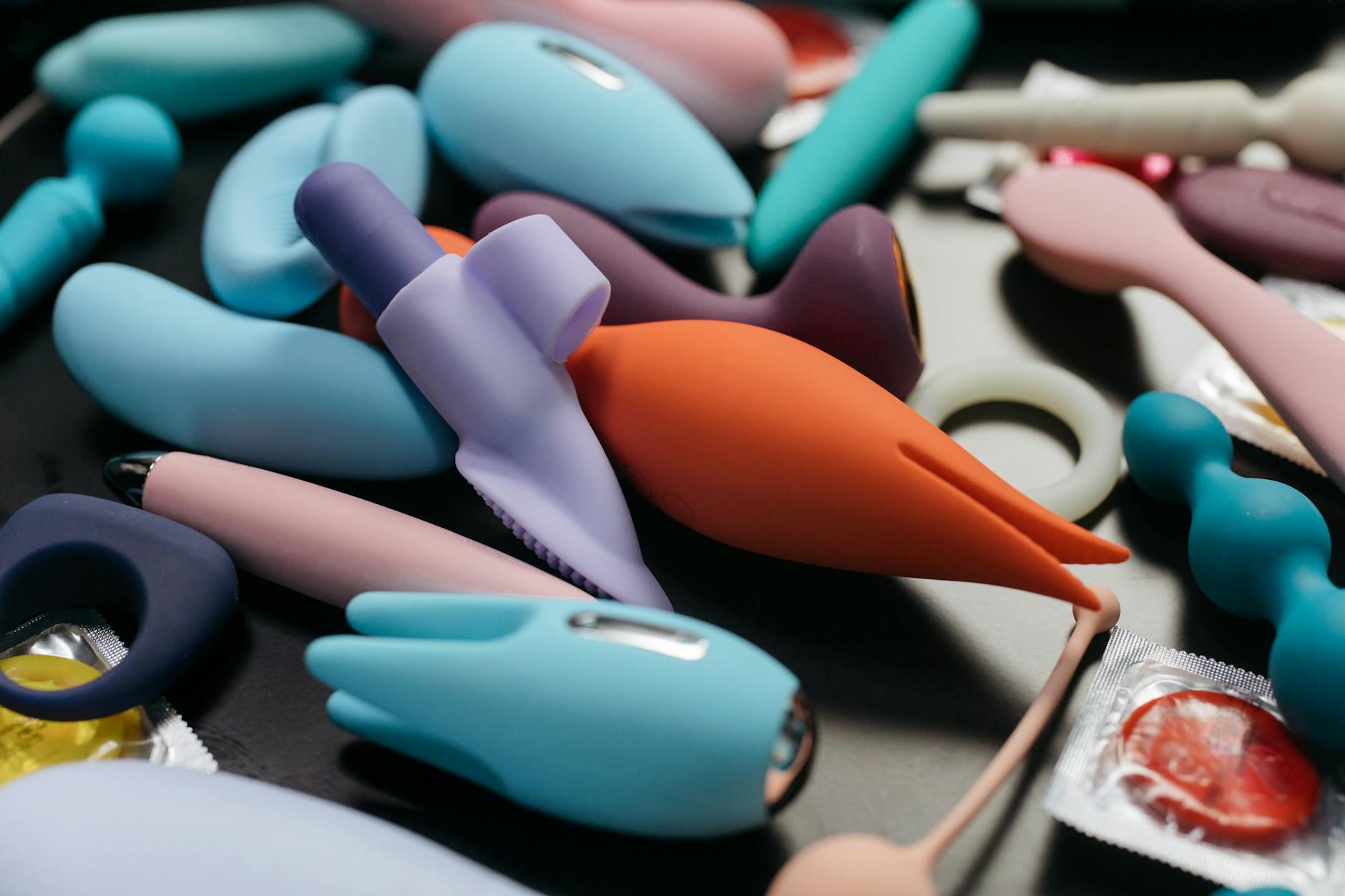 Close-up of a hand holding a modern clitoral vibrator against a purple background, showcasing sensual design