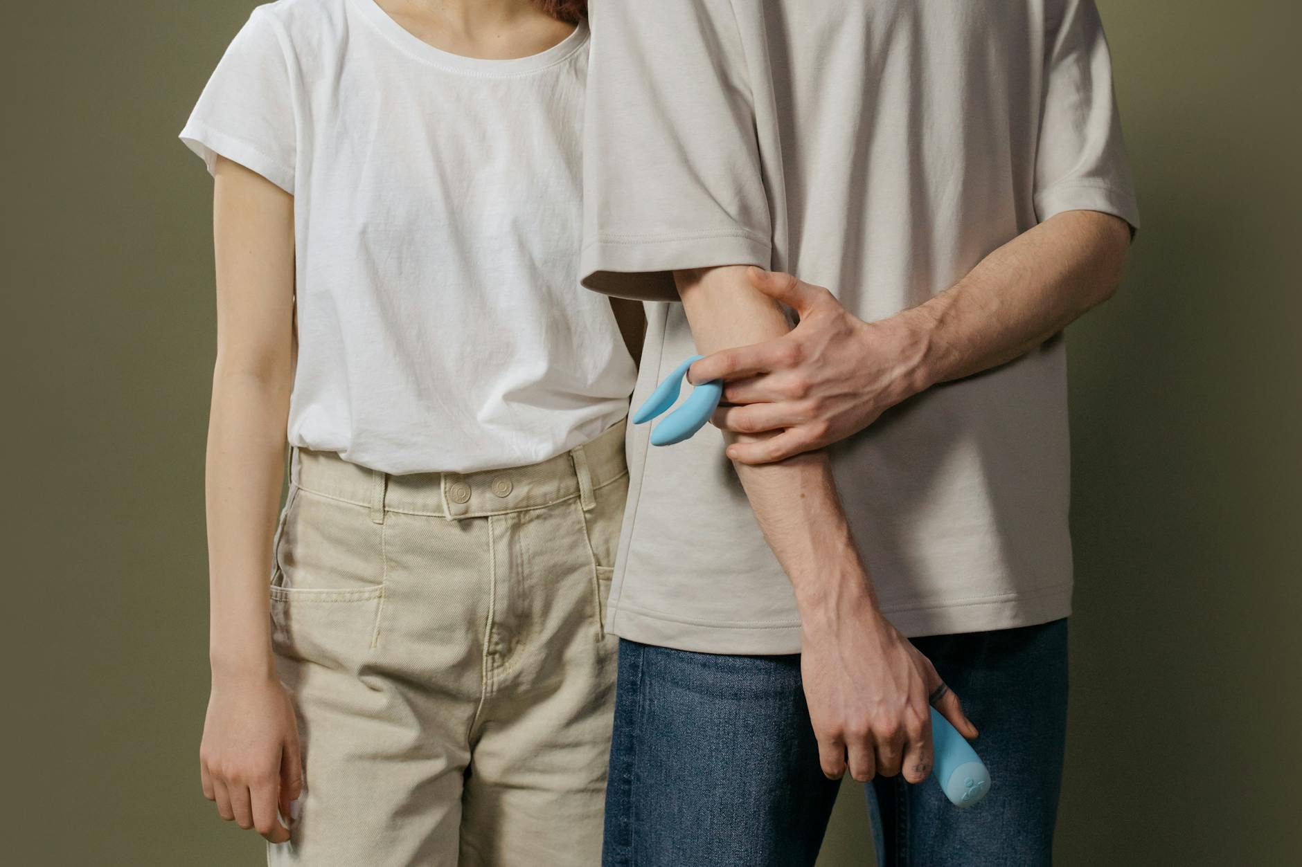 Una mujer sosteniendo vibradores de silicona azul y rosa, considerando opciones de placer y exploración.
